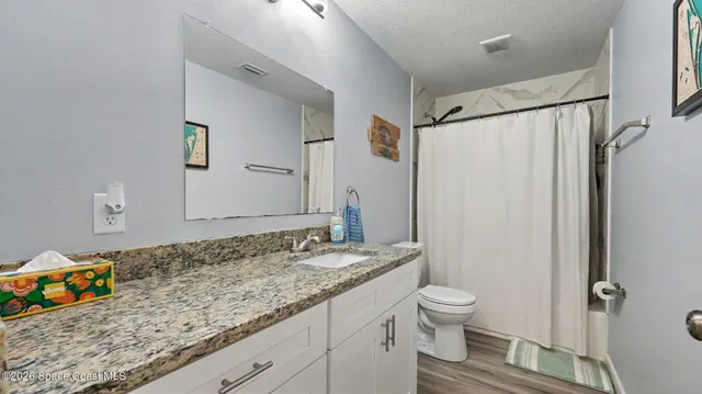 a bathroom with a granite countertop sink toilet and shower
