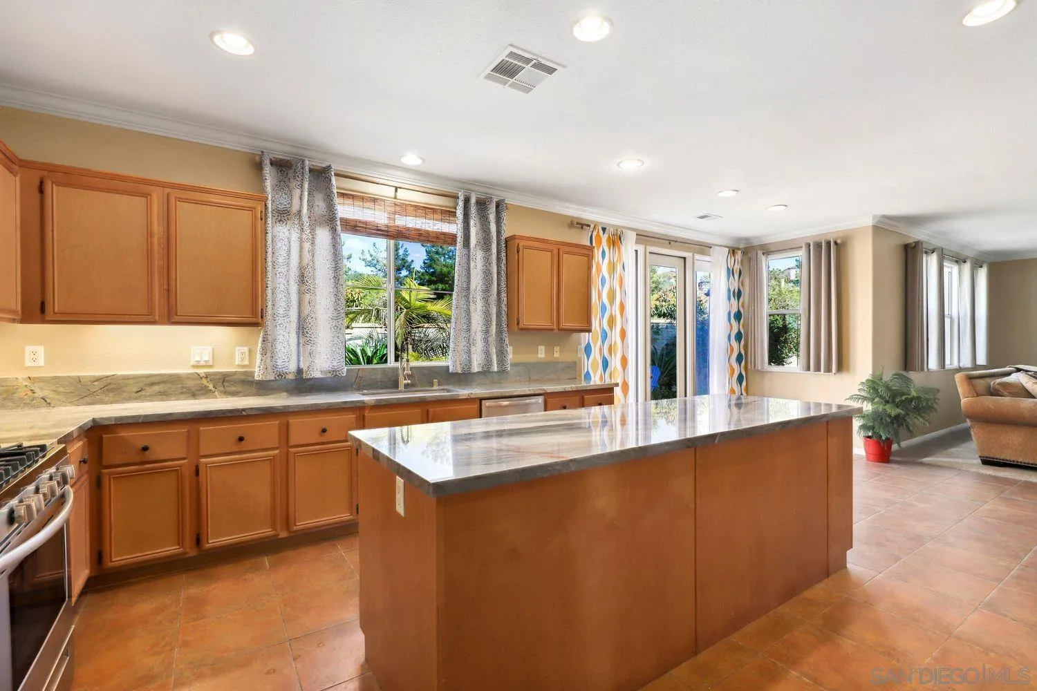 1166 Midnight Way Oceanside, CA 92057 - Photo 8 of 37 a large kitchen with kitchen island granite countertop a sink and dishwasher wooden cabinets with a large window