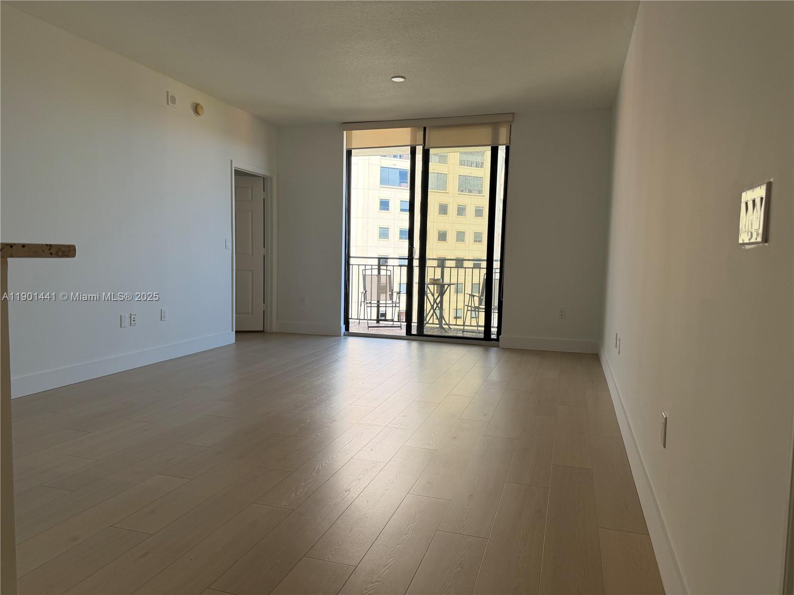 888 Douglas Road, Unit 917 Coral Gables, FL 33134 - Photo 13 of 31 an empty room with wooden floor and windows with curtains