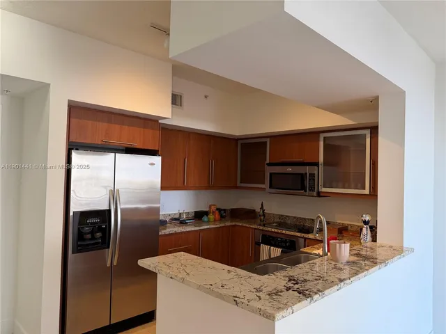 a kitchen with stainless steel appliances granite countertop a sink refrigerator and microwave