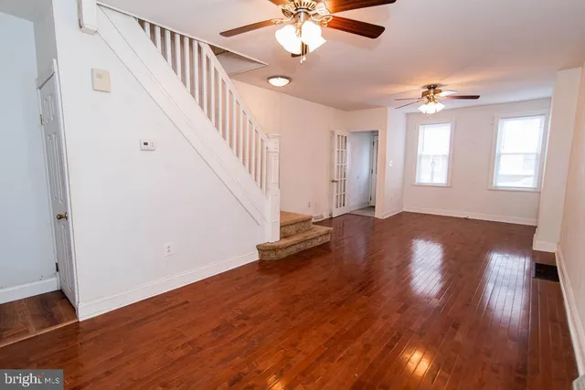 a view of empty room with wooden floor and fan