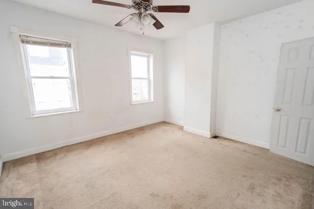an empty room with windows and fan