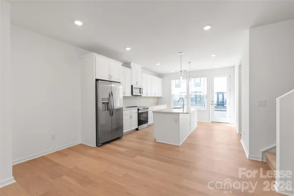 a view of a kitchen with refrigerator microwave and wooden floor