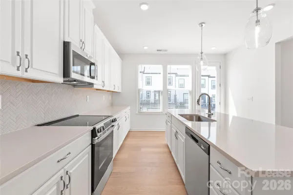 a kitchen with stainless steel appliances granite countertop a sink a stove and a wooden floors