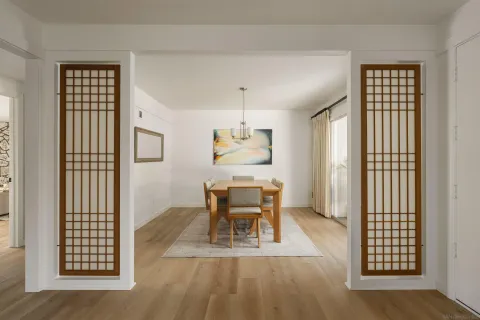 a dining room with wooden floor a glass table and chairs