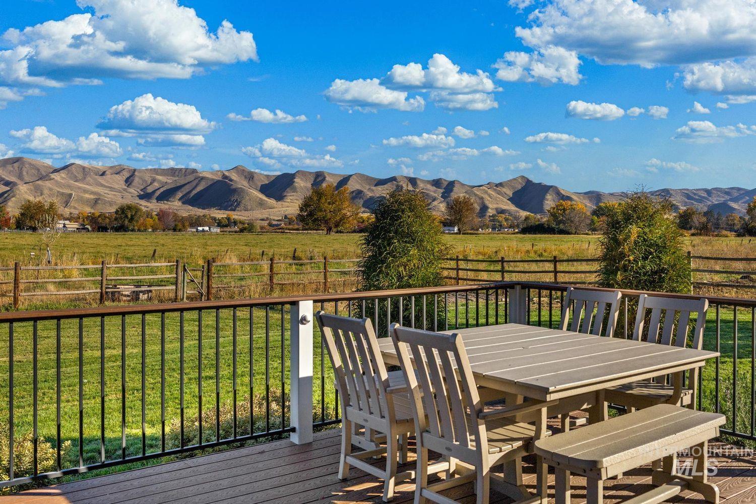 2185 Waterwheel Road Emmett, ID 83617 - Photo 16 of 49 Wooden deck featuring a fenced backyard, a view of countryside, a mountain view, and outdoor dining area