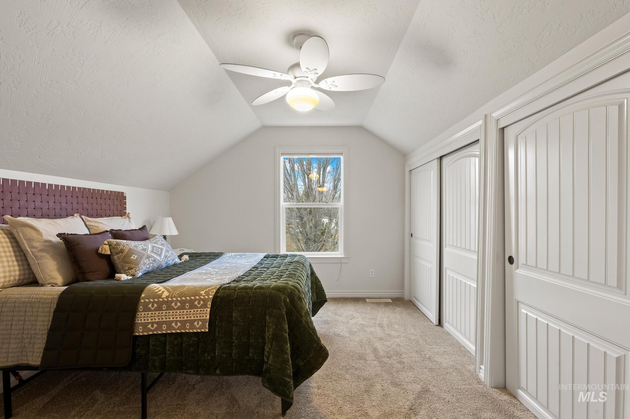 2185 Waterwheel Road Emmett, ID 83617 - Photo 37 of 49 Bedroom featuring multiple closets, light colored carpet, vaulted ceiling, a ceiling fan, and a textured ceiling