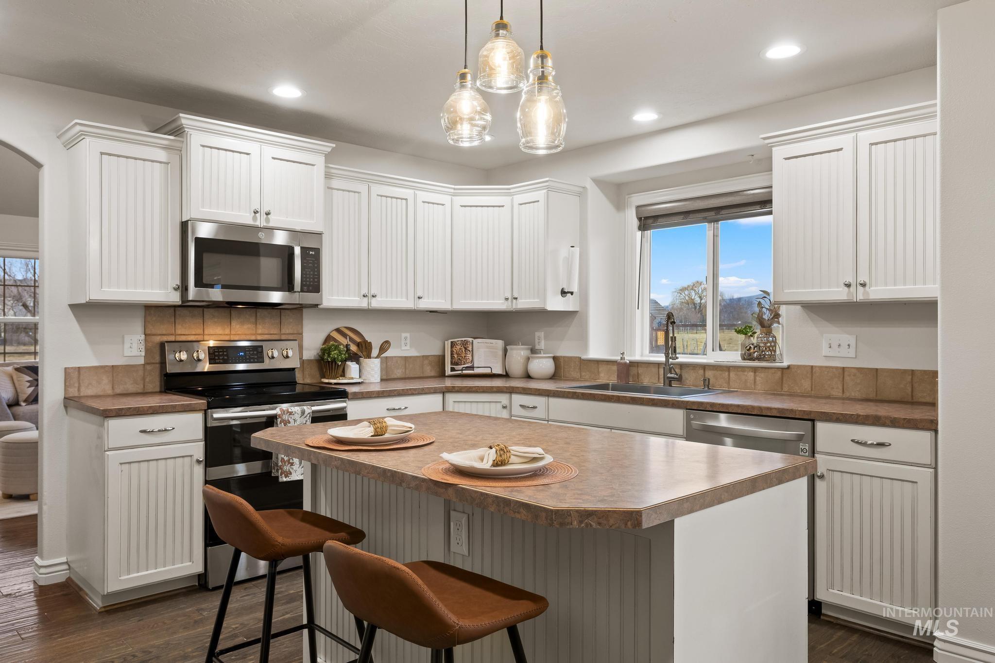 2185 Waterwheel Road Emmett, ID 83617 - Photo 7 of 49 Kitchen with appliances with stainless steel finishes, dark wood finished floors, a breakfast bar, a center island, and white cabinetry