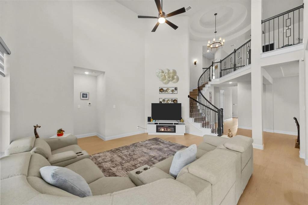 10969 Coastal Violet Road Frisco, TX 75035 - Photo 4 of 30 Living area featuring a towering ceiling, stairs, light wood-type flooring, ceiling fan, and a chandelier