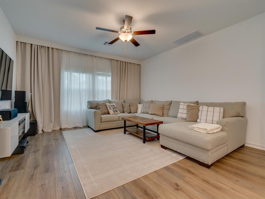 1208 Sweetspire Street Leander, TX 78641 - Photo 10 of 36 Living area featuring wood-finish flooring, a ceiling fan with integrated lighting, and a window with layered drapery