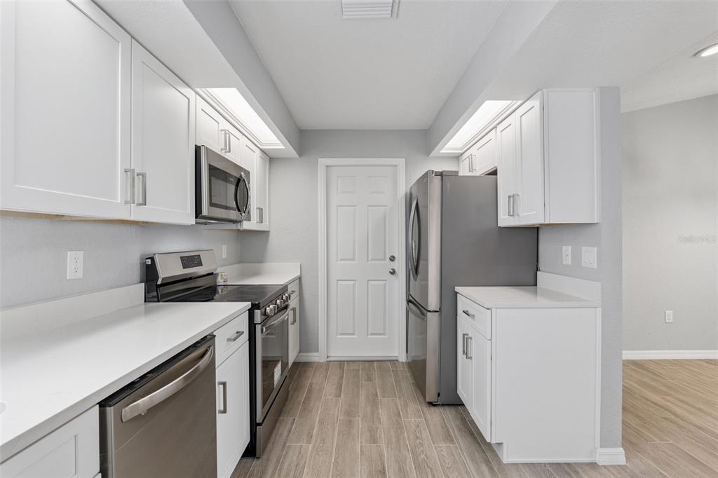 1932 Maple Circle, Unit 1932 Tavares, FL 32778 - Photo 9 of 39 a kitchen with stainless steel appliances a stove a sink a refrigerator white cabinets and wooden floor
