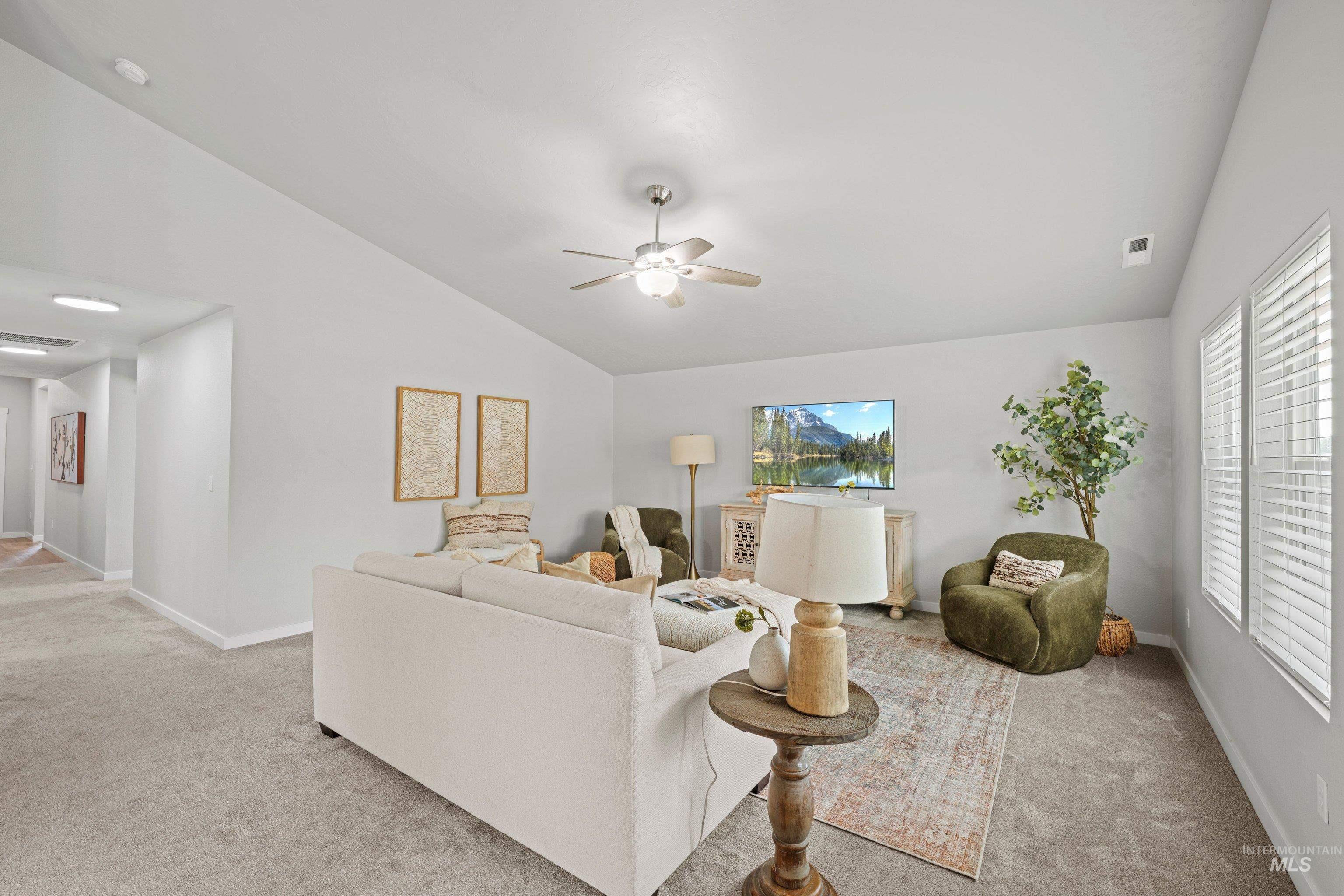 12744 West Fig Street Boise, ID 83713 - Photo 8 of 34 Spacious living area featuring vaulted ceilings, neutral carpeting, and a ceiling fan with integrated lighting