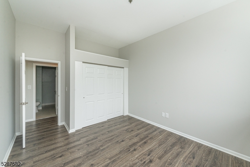 240 Main Street, Unit 313 Little Falls, NJ 07424 - Photo 16 of 21 a view of an empty room with wooden floor and closet