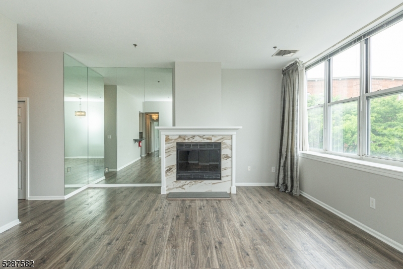 240 Main Street, Unit 313 Little Falls, NJ 07424 - Photo 2 of 21 a view of an empty room with wooden floor fireplace and a window