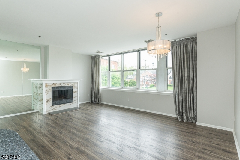 240 Main Street, Unit 313 Little Falls, NJ 07424 - Photo 3 of 21 an empty room with wooden floor fireplace and windows