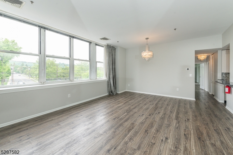 240 Main Street, Unit 313 Little Falls, NJ 07424 - Photo 4 of 21 an empty room with wooden floor and windows