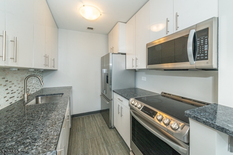 240 Main Street, Unit 313 Little Falls, NJ 07424 - Photo 6 of 21 a kitchen with stainless steel appliances granite countertop a stove a microwave and a sink