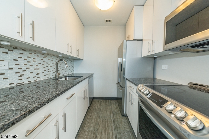 240 Main Street, Unit 313 Little Falls, NJ 07424 - Photo 7 of 21 a kitchen with granite countertop a sink and a stove