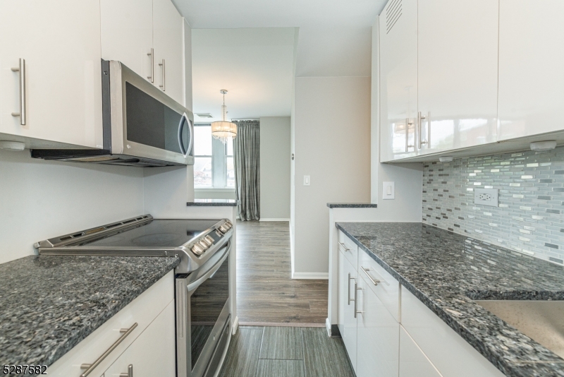 240 Main Street, Unit 313 Little Falls, NJ 07424 - Photo 8 of 21 a kitchen with granite countertop a sink a stove and cabinets