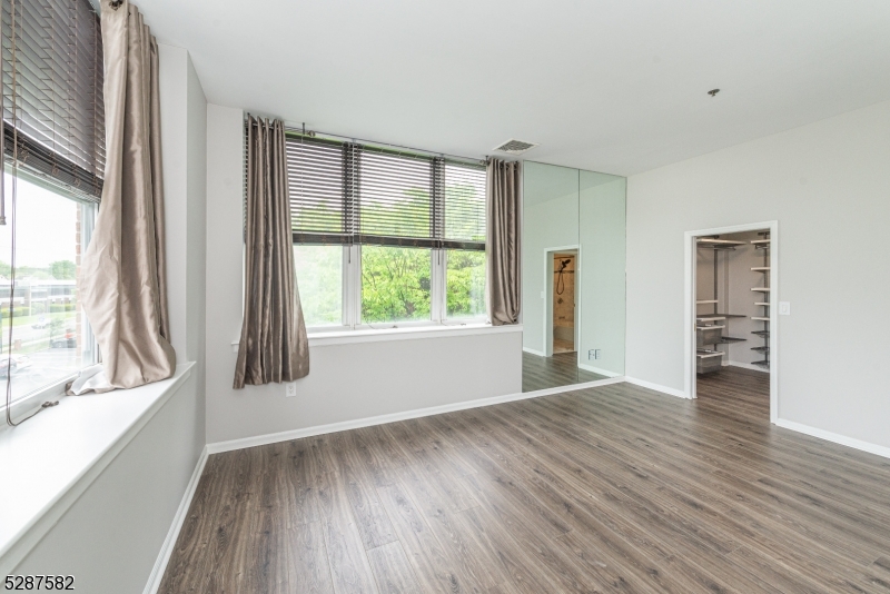 240 Main Street, Unit 313 Little Falls, NJ 07424 - Photo 10 of 21 a view of an empty room with a window and wooden floor
