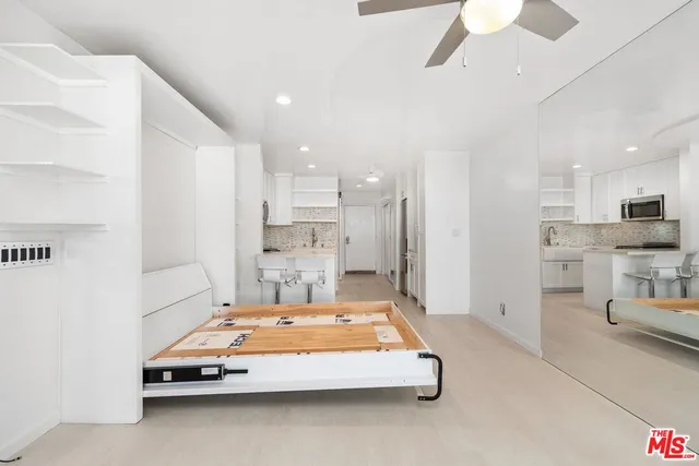 a view of a kitchen with kitchen island white cabinets and stainless steel appliances