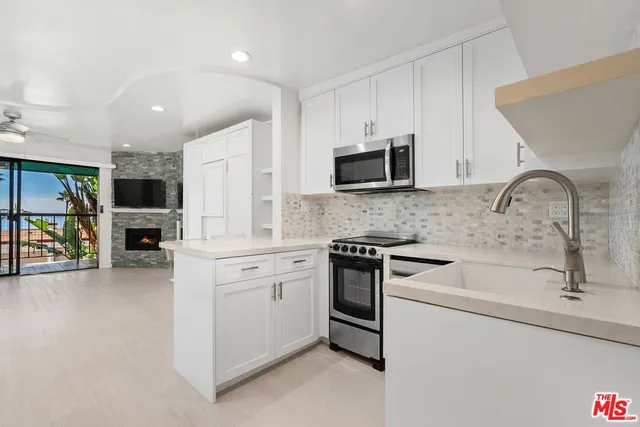 a kitchen with white cabinets a sink and appliances