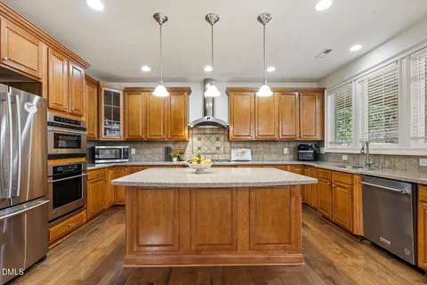 a large kitchen with kitchen island a large counter top stainless steel appliances and windows