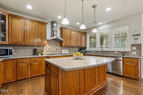 a kitchen with stainless steel appliances granite countertop a sink a stove and a wooden cabinets