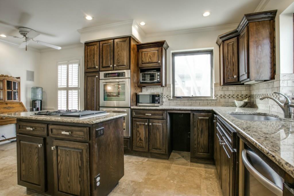 5419 Merrimac Avenue Dallas, TX 75206 - Photo 11 of 17 Kitchen featuring an island with a gas cooktop, granite countertops, wood cabinetry, stainless steel appliances, and tile flooring