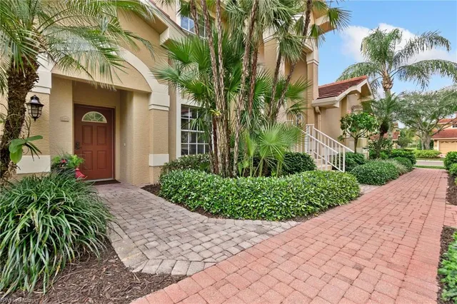 a front view of a house with a yard and potted plants