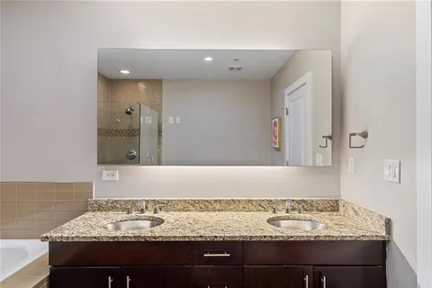 a bathroom with a granite countertop sink a mirror a bathtub and shower