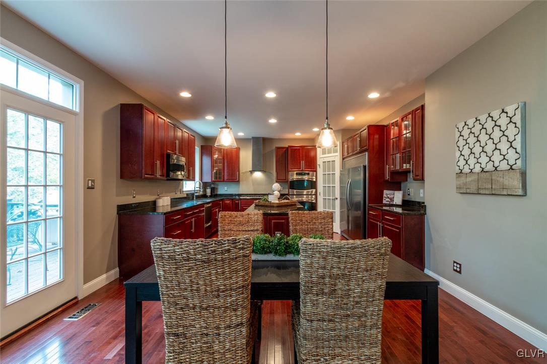 3153 Olympic Drive Emmaus, PA 18049 - Photo 15 of 40 a kitchen with stainless steel appliances kitchen island granite countertop a refrigerator a stove a sink dishwasher and a dining table with wooden floor