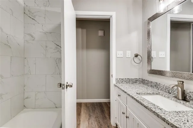 a bathroom with a granite countertop sink a mirror and a bathtub