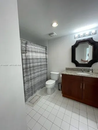 a bathroom with a granite countertop sink a toilet and a shower