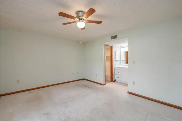 an empty room with a chandelier fan and windows