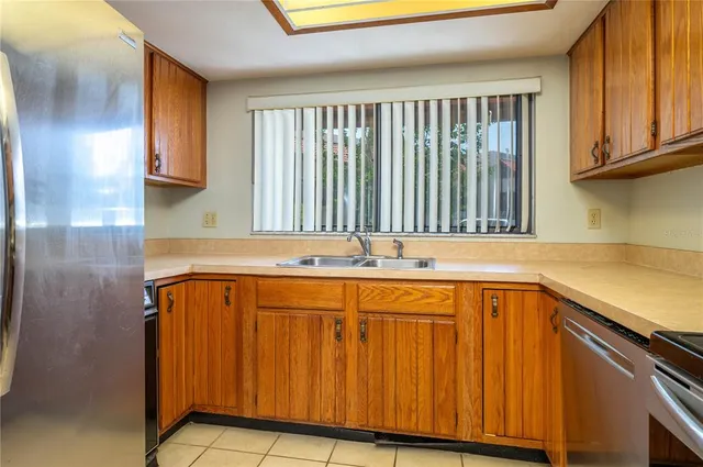 a utility room with stainless steel appliances granite countertop wooden cabinets a sink and dishwasher