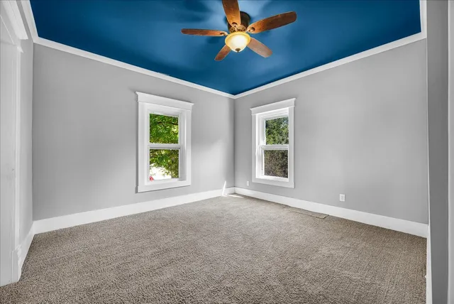an empty room with windows and a ceiling fan