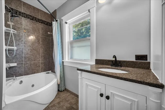a bathroom with a granite countertop sink and a bathtub