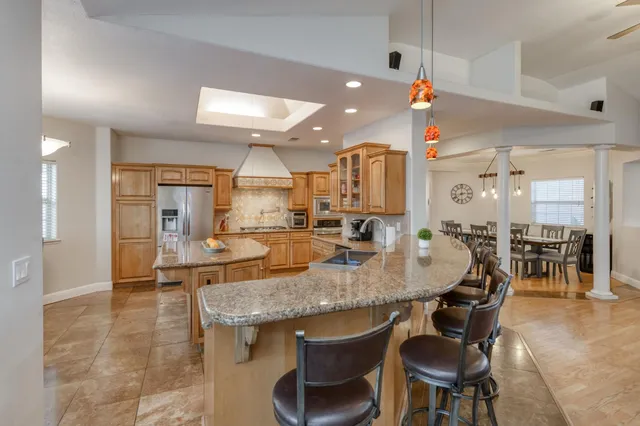 a kitchen with stainless steel appliances kitchen island granite countertop a refrigerator and a stove top oven