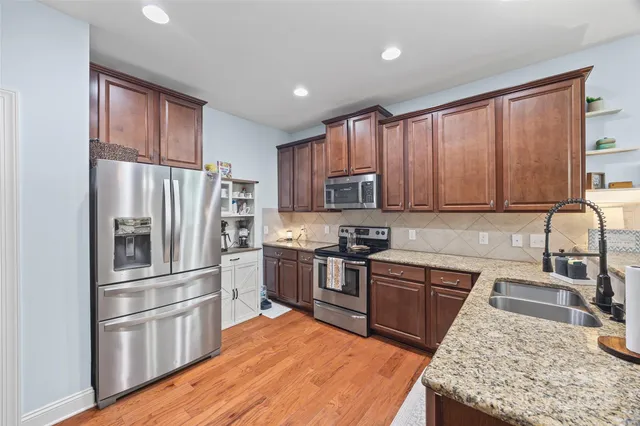 a kitchen with stainless steel appliances granite countertop a refrigerator stove and sink