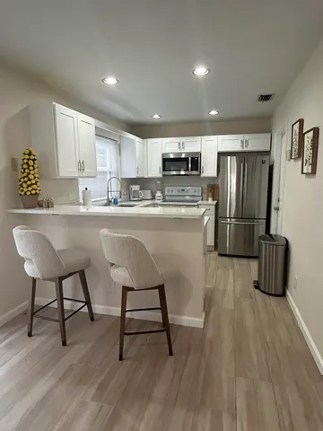 a kitchen with stainless steel appliances a refrigerator a stove a sink dishwasher and a chair with wooden floor