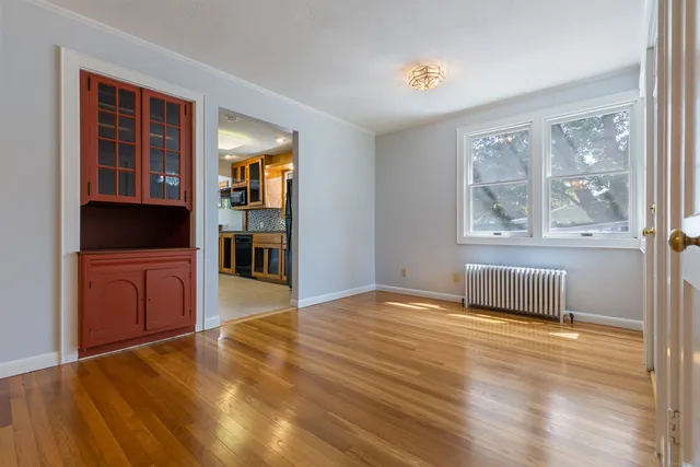 a view of an empty room with glass door and wooden floor