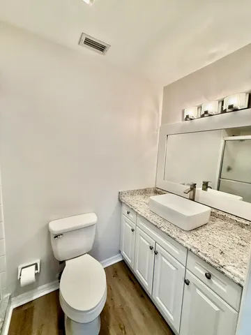 a bathroom with a granite countertop toilet sink and mirror
