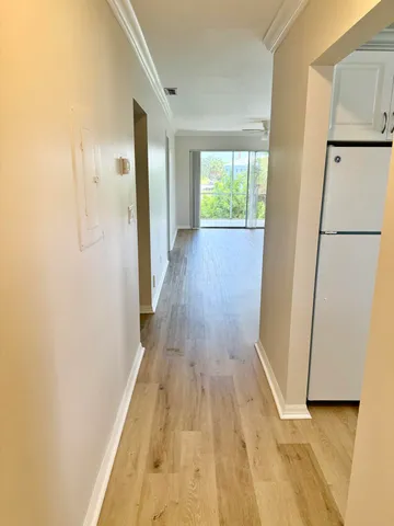 a view of a hallway with wooden floor and a refrigerator