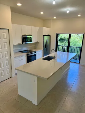 a kitchen with kitchen island granite countertop a large counter top stainless steel appliances a sink and cabinets