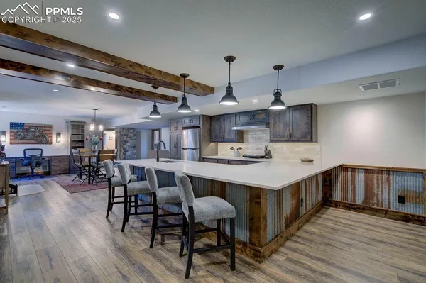 a kitchen with stainless steel appliances a dining table chairs refrigerator and sink