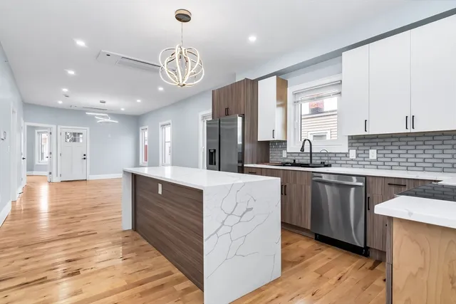 a large kitchen with stainless steel appliances granite countertop a stove and wooden cabinets