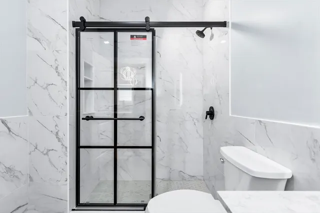 a white toilet sitting next to a shower