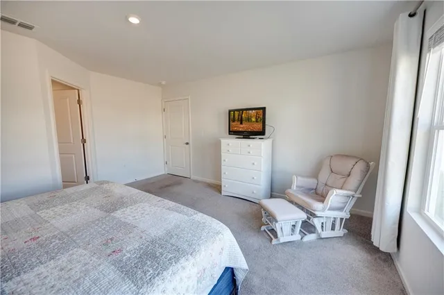 a spacious bedroom with a bed and a chair