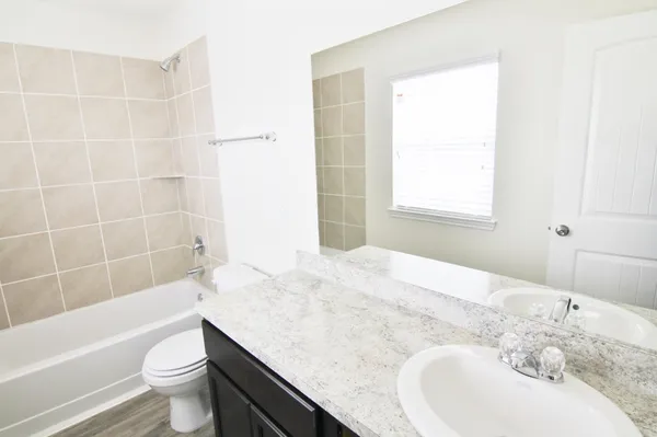 a bathroom with a granite countertop sink a toilet and bathtub